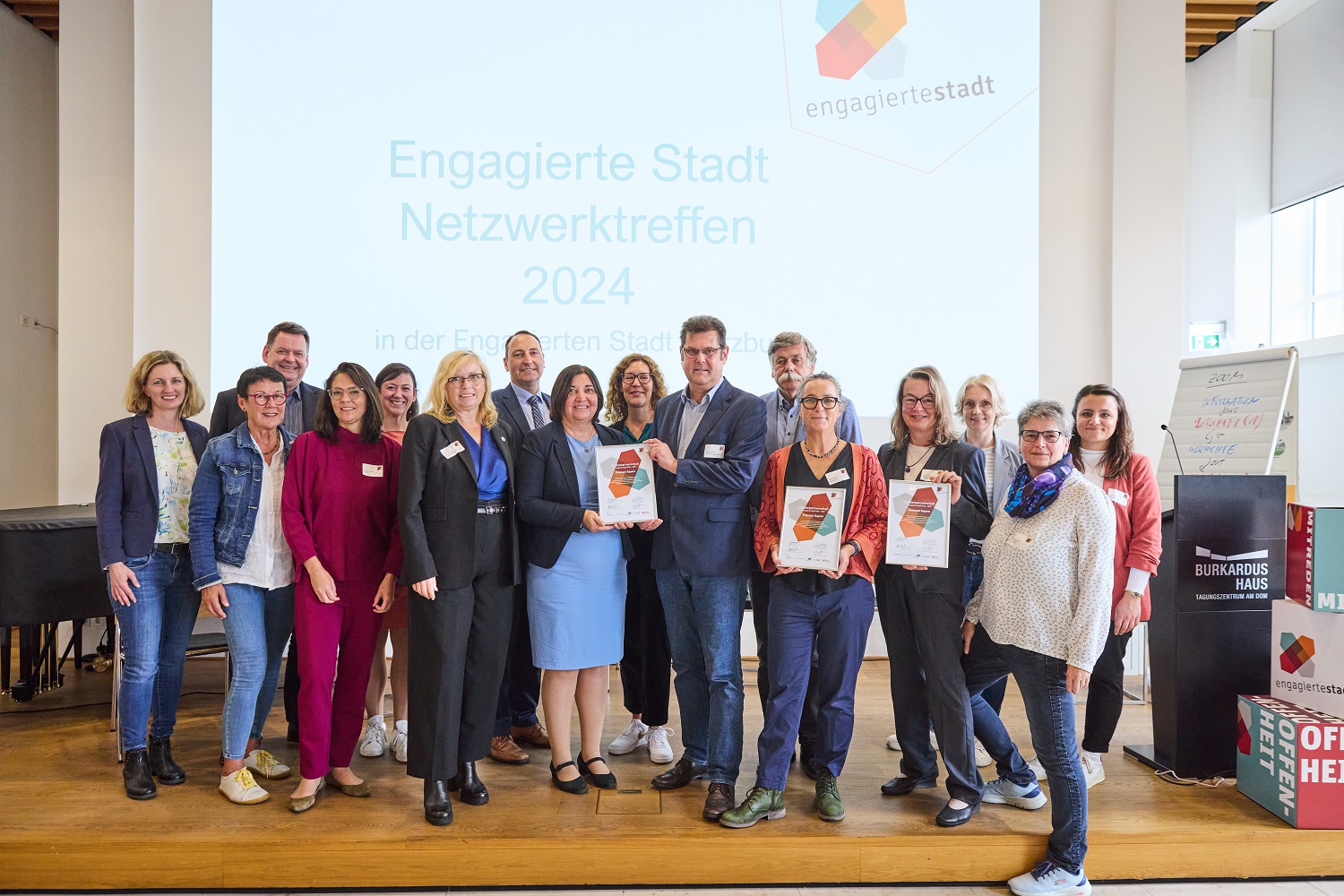 Foto vom Netzwerktreffen von Gruppe mit Landesvertrag mit Ekin Deligöz (parlamentarische Staatssekretärin), Hilmar Holzner (Bayerisches Staatsministerium für Familie, Arbeit und Soziales), Gabi Schmidt (Ehrenamtsbeauftragte Freistaat Bayern), Claudia Leitzmann (LBE Bayern), Beatrix Hertle (lagfa Bayern), Daniela van Wyk (BMFSFJ), Dr. Lilian Schwalb (BBE), Andreas Grau (Bertelsmann Stiftung), Frank Strathmann (Engagierte Stadt Holzkirchen), Daniela Schulte (Engagierte Stadt Puchheim), Sabine Nuber (Engagierte Stadt Kronach), Anna Lehrer (Engagierte Stadt Neumarkt), Judith Himmler (Engagierte Stadt Neumarkt), Wibke Limmer (Engagierte Stadt Würzburg), Cyana Pompeo Schuster (Engagierte Stadt Würzburg), Kristin Funk (Engagierte Stadt Würzburg)